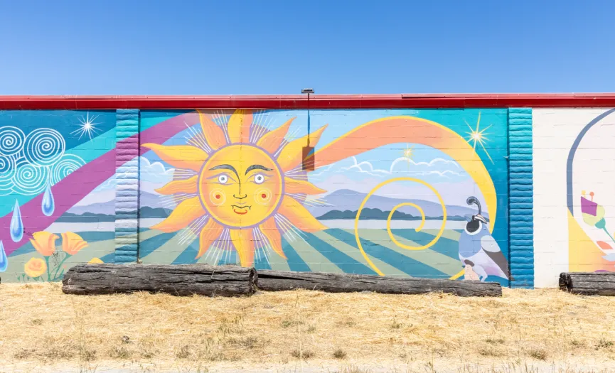 South wall mural with a stylized sun, swirling wind, and farm-themed imagery near Security Public Storage at 271 Sun Way in Salinas, CA