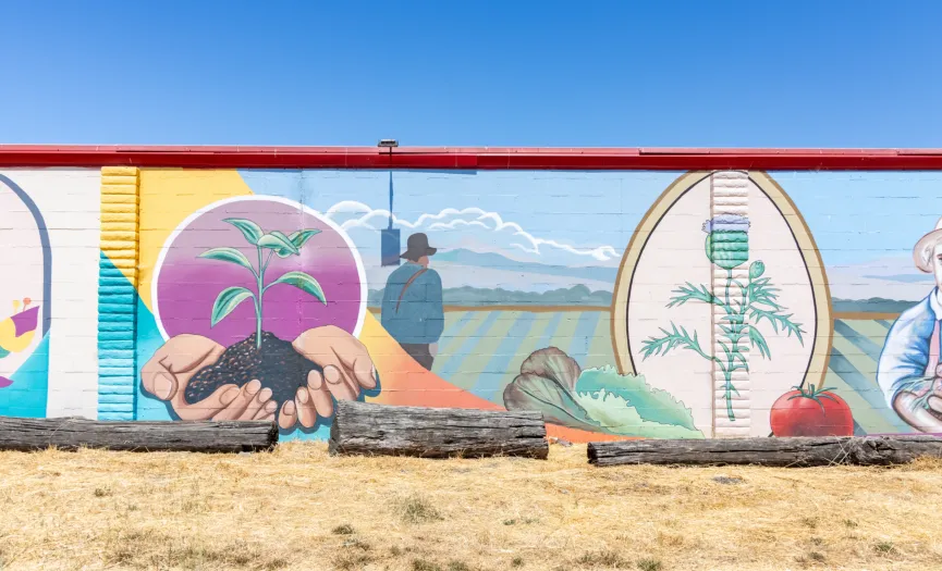 South wall mural showing hands holding a seedling, farm fields, and produce imagery near Security Public Storage at 271 Sun Way, Salinas CA
