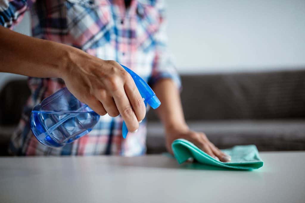 Keep your storage unit clean, man spraying item in storage unit to remove dust